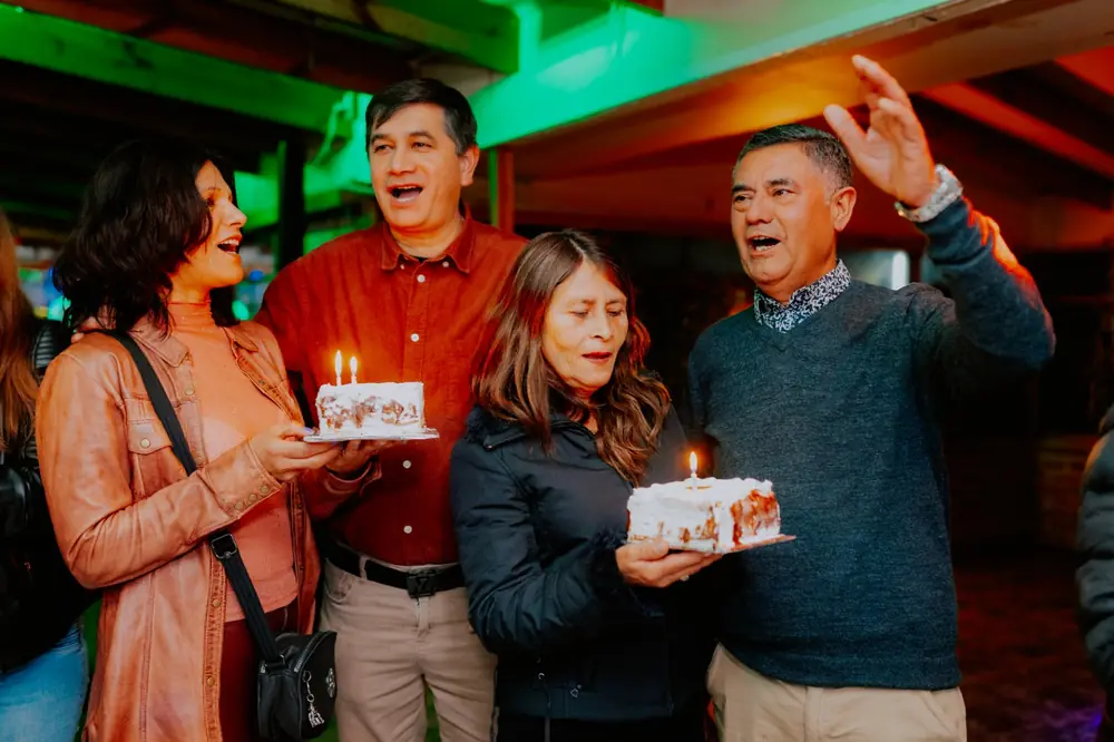Amigos cantando el cumpleaños con dos tortas
